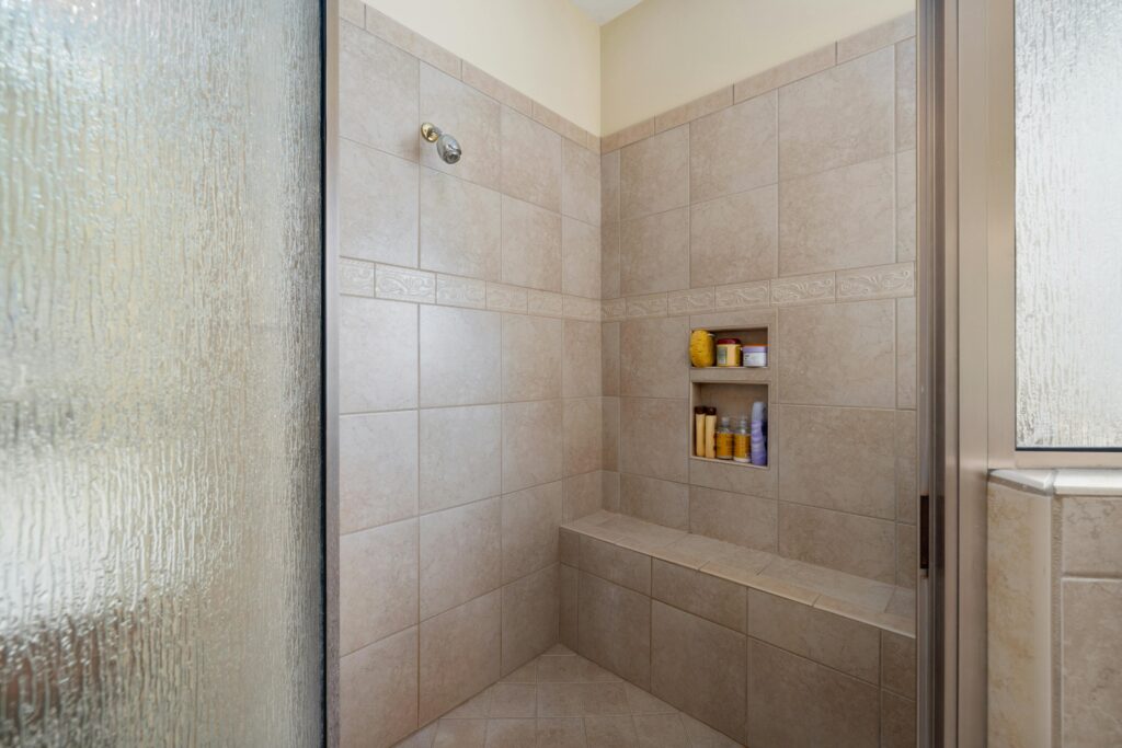 pexels-photo-12700514-12700514 Elegant walk-in shower with beige tiles and built-in shelves, perfect for a modern bathroom.